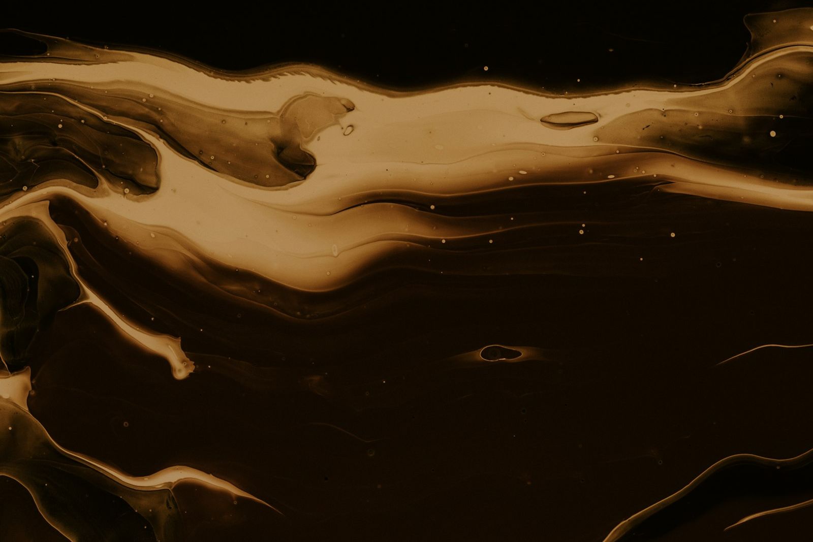 Golden oil swirling across a dark surface