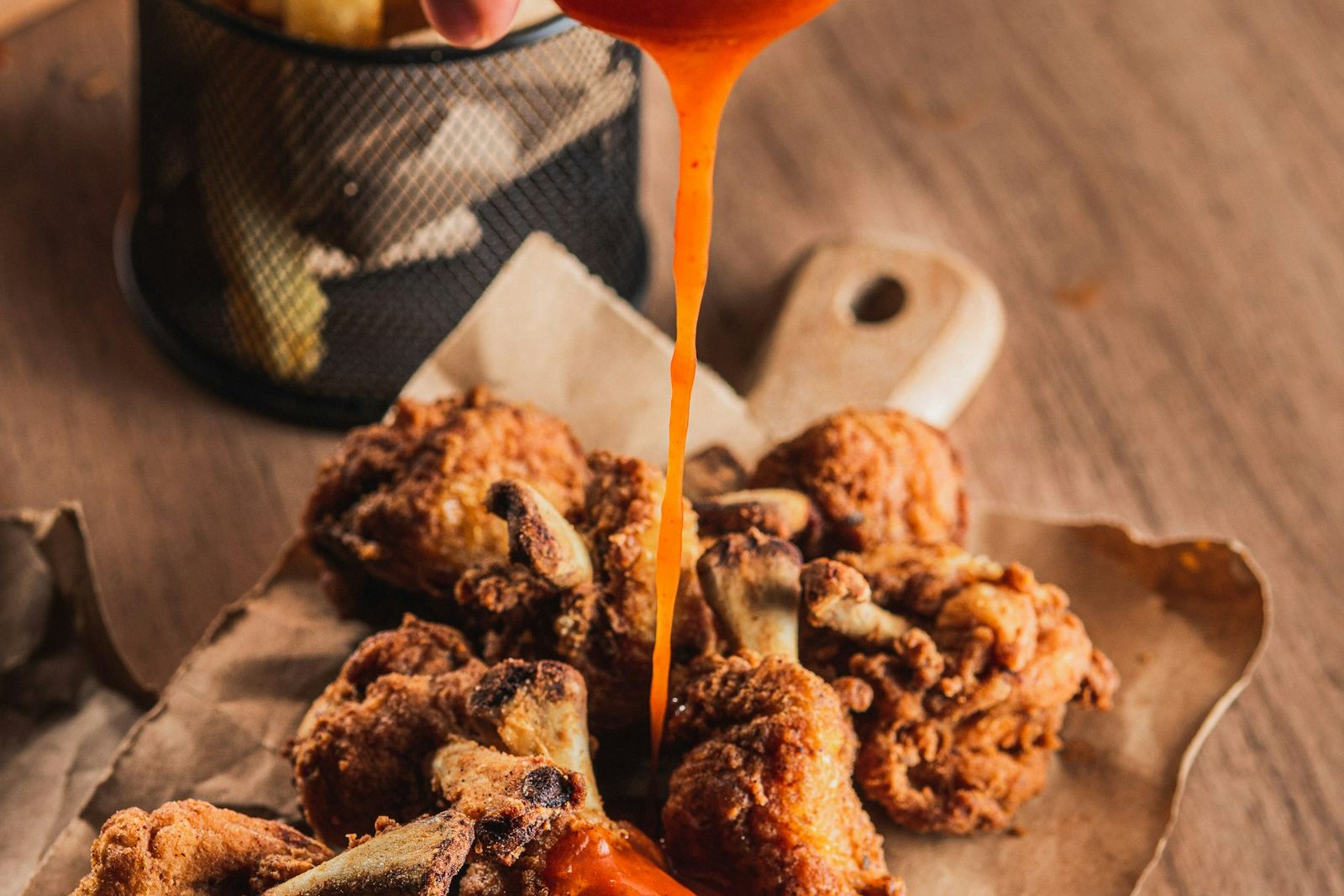 Hot sauce being poured over fried chicken