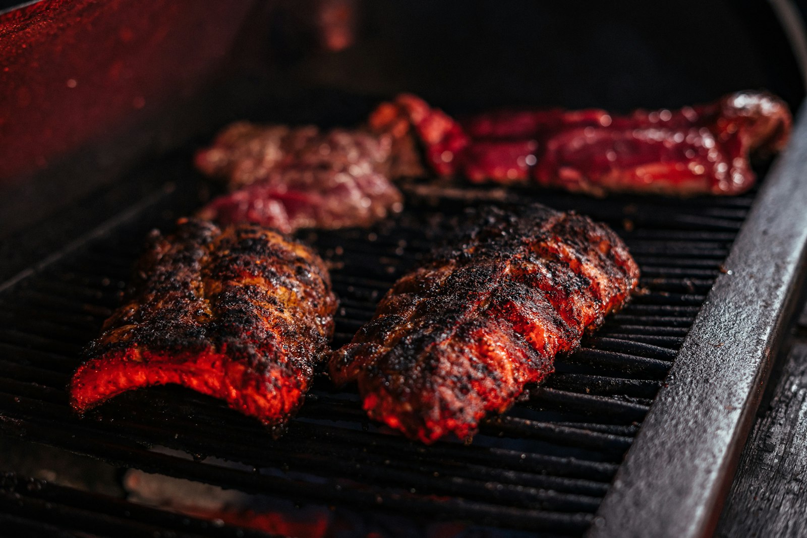 Charred, seasoned ribs smoking on a grill