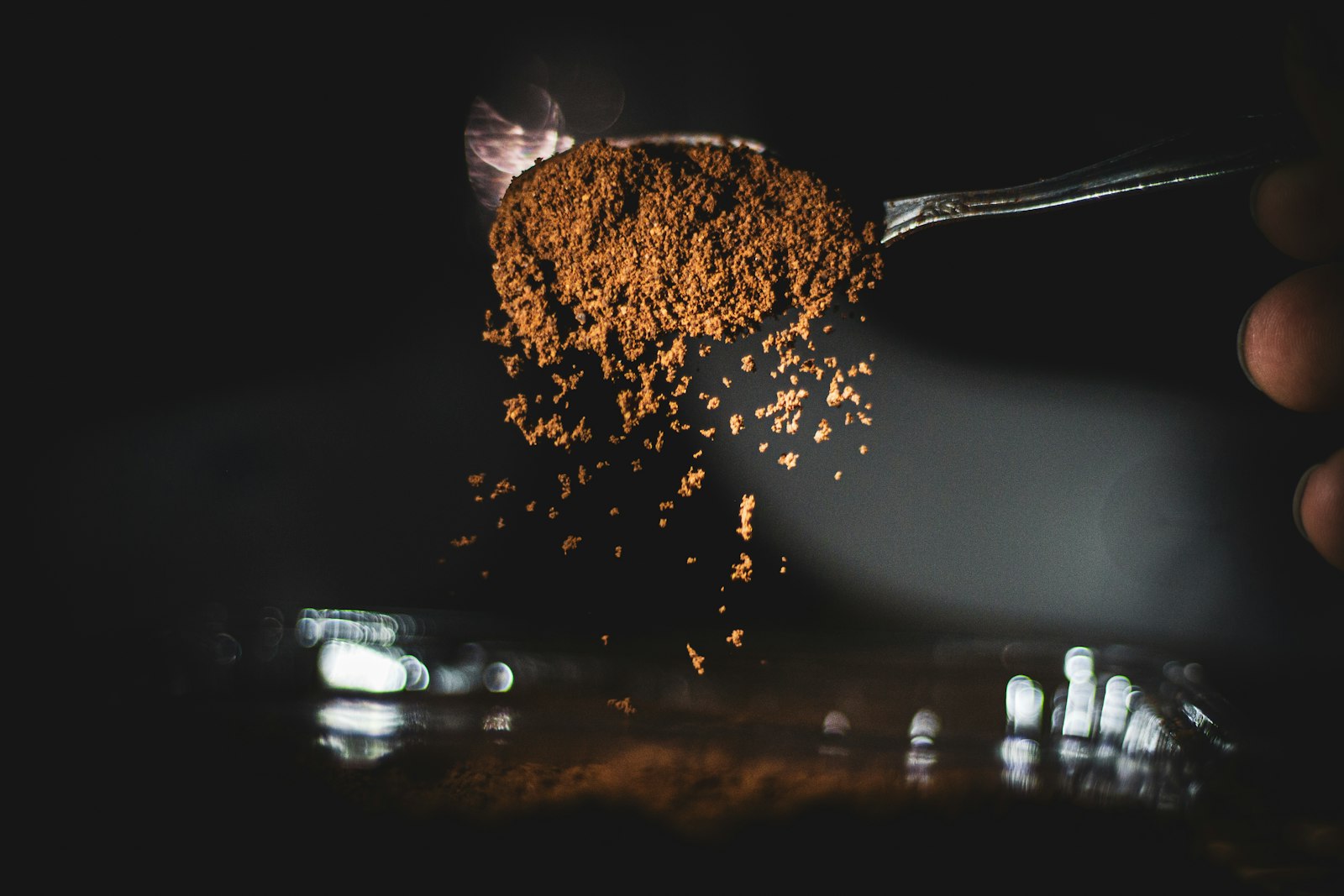A spoonful of ground spice powder falling into shadow